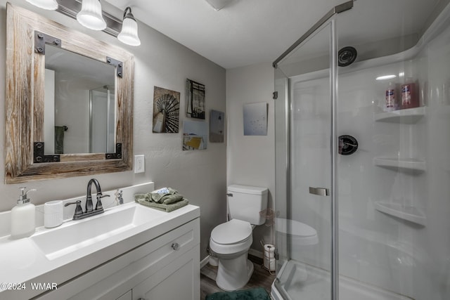 full bath with wood finished floors, a stall shower, vanity, and toilet