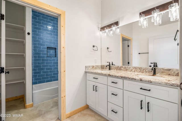 bathroom featuring double vanity, tile patterned floors, a sink, and baseboards