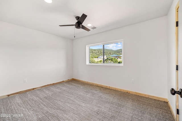 carpeted empty room featuring baseboards, visible vents, and ceiling fan