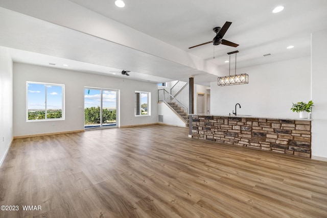 unfurnished living room with stairway, wood finished floors, a ceiling fan, and recessed lighting