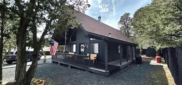 rear view of house with a shingled roof, fence, and a wooden deck