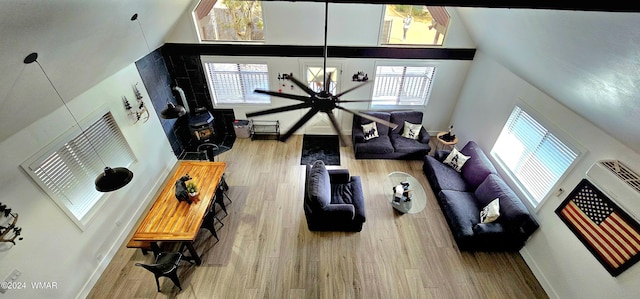 living room with a healthy amount of sunlight, a towering ceiling, baseboards, and wood finished floors