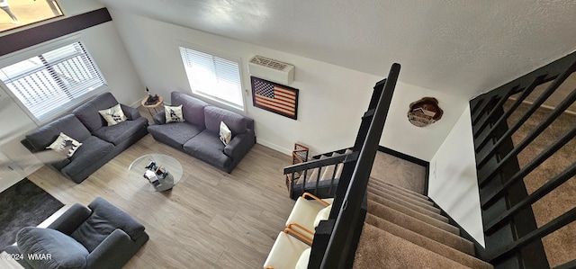 living room with stairs, a textured ceiling, baseboards, and wood finished floors