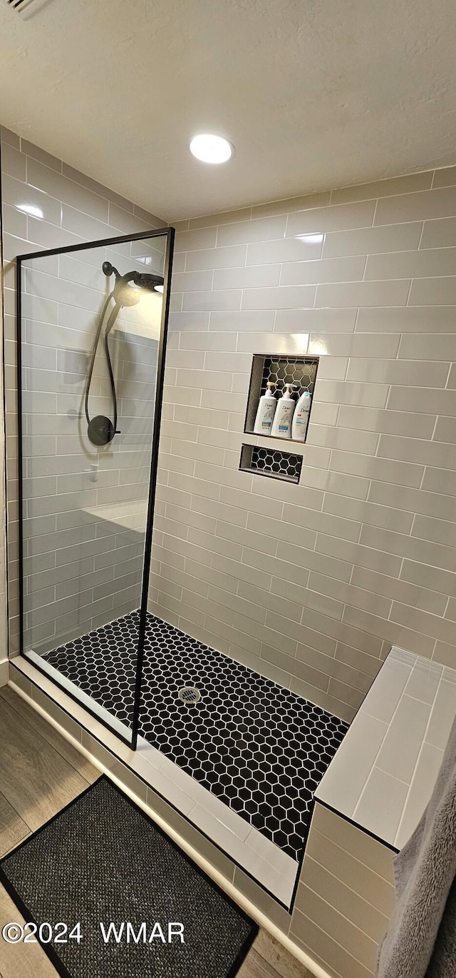 bathroom with recessed lighting, a shower stall, and wood finished floors