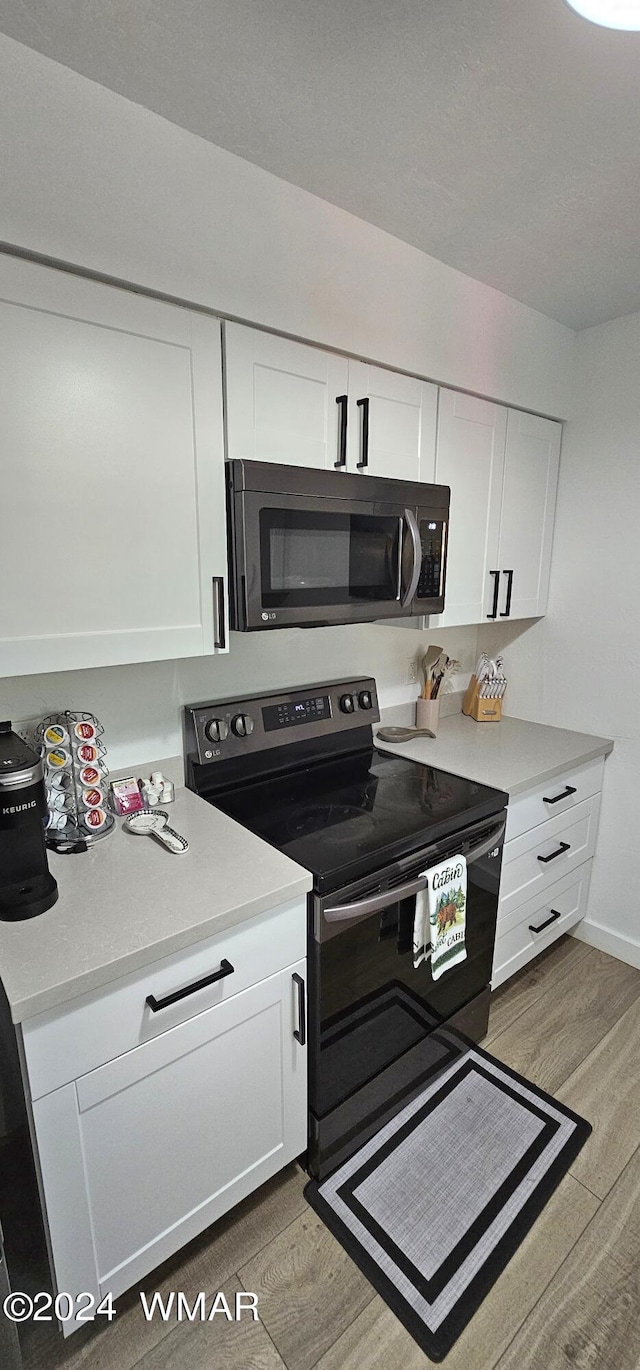 kitchen with light countertops, electric range, and white cabinetry