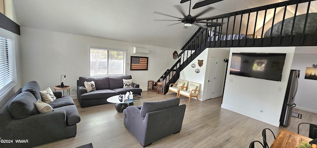 living room with lofted ceiling, stairway, an AC wall unit, wood finished floors, and baseboards