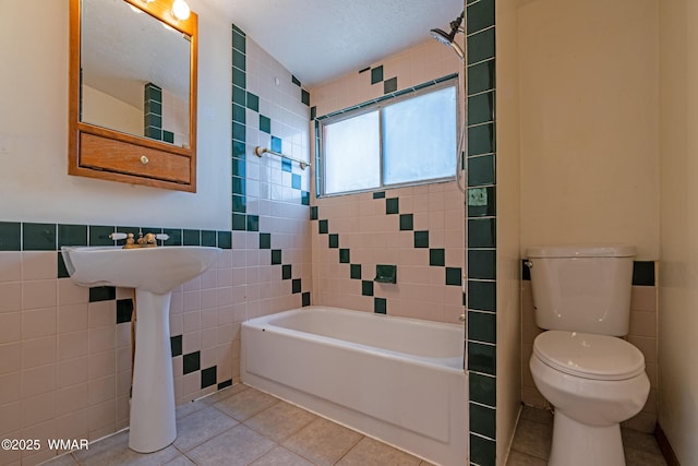 full bathroom featuring tile walls, tile patterned floors, toilet, and washtub / shower combination