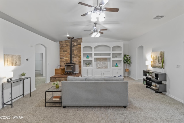 3401 W Hansen, Show Low, AZ 85901 - carpeted living room featuring arched walkways, vaulted ceiling, a wood stove, ceiling fan, and baseboards