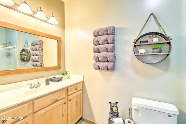 bathroom with vanity, toilet, and a shower with shower door