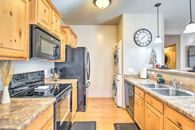 kitchen with light brown cabinets, stacked washer and clothes dryer, light wood-style floors, black appliances, and a sink