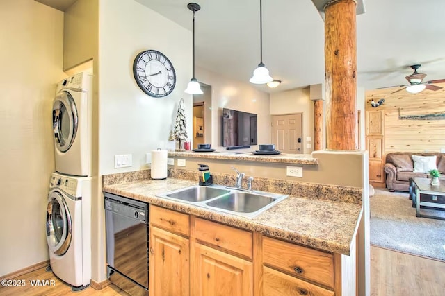 kitchen with stacked washer and clothes dryer, a sink, light wood-style floors, a peninsula, and dishwasher