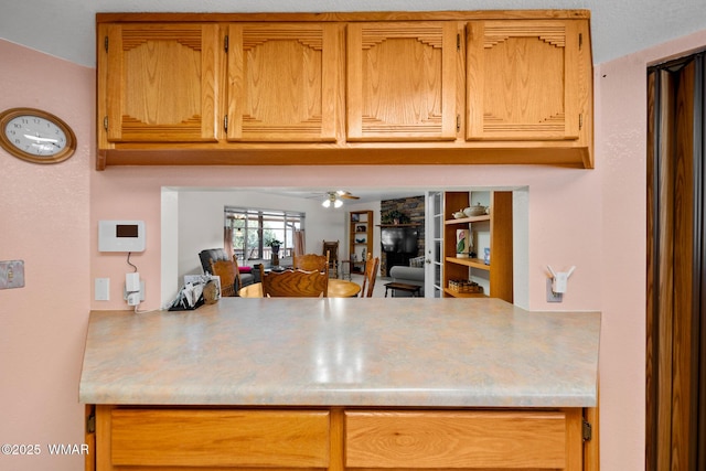 kitchen featuring a peninsula, light countertops, and ceiling fan