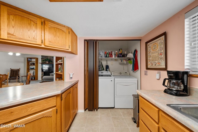 kitchen with washer and clothes dryer, light tile patterned floors, light countertops, and a sink