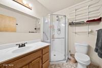 bathroom featuring toilet, a stall shower, and vanity