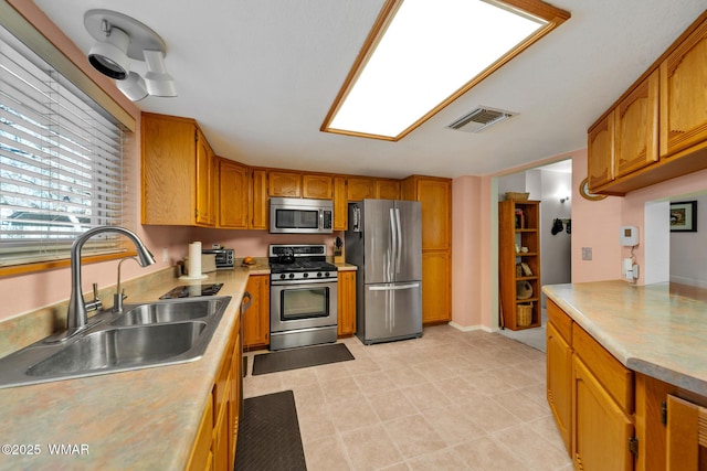 kitchen featuring visible vents, light countertops, brown cabinets, appliances with stainless steel finishes, and a sink