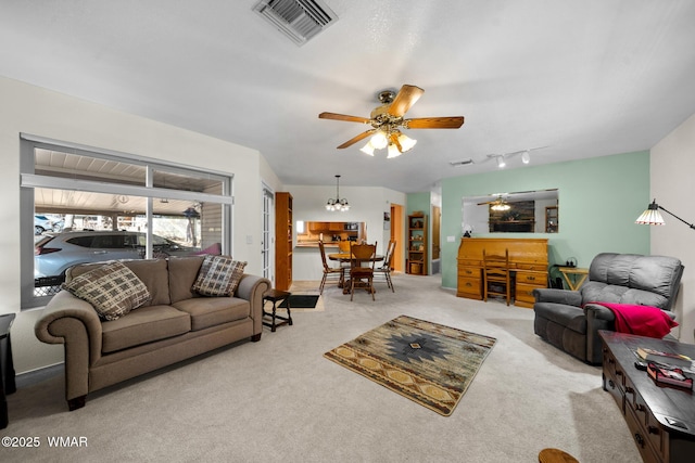 living room featuring visible vents, carpet flooring, and ceiling fan with notable chandelier