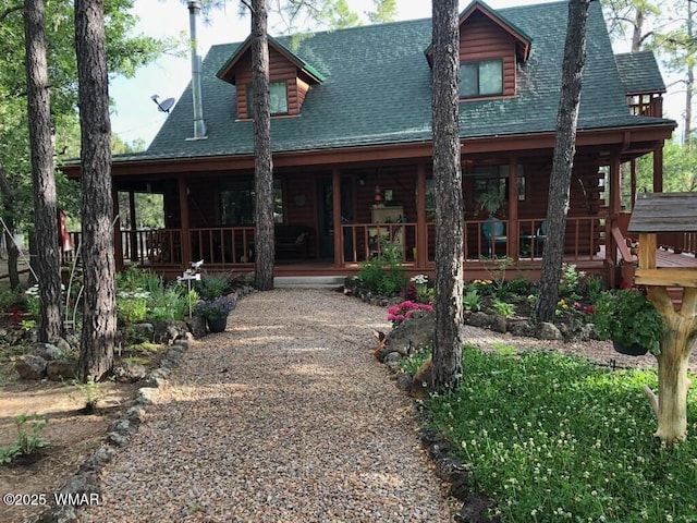 back of property with log exterior, a porch, and a shingled roof