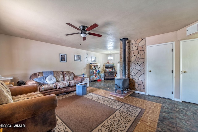 living area with a ceiling fan, a wood stove, and baseboards