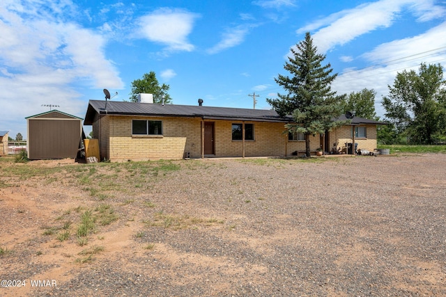 view of front of house with an outbuilding, brick siding, and a shed