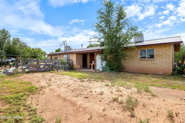 rear view of property with metal roof and brick siding