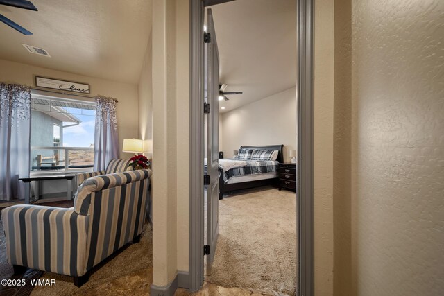 hallway with carpet, visible vents, and a textured wall