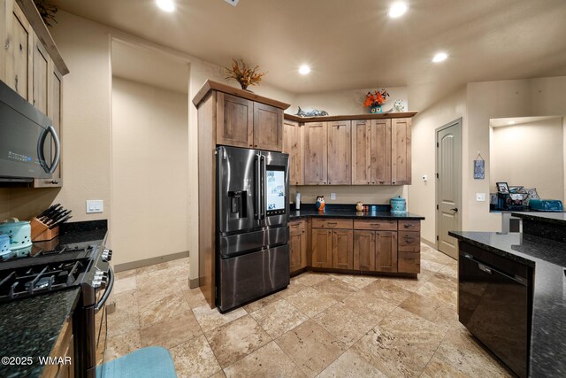 kitchen with baseboards, appliances with stainless steel finishes, brown cabinets, dark stone countertops, and recessed lighting