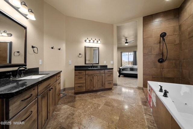 bathroom featuring a tub with jets, two vanities, a sink, and ensuite bathroom