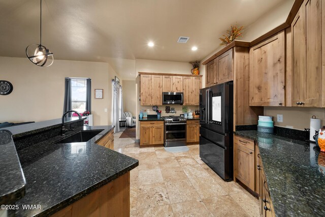 kitchen with appliances with stainless steel finishes, dark stone countertops, a sink, and pendant lighting