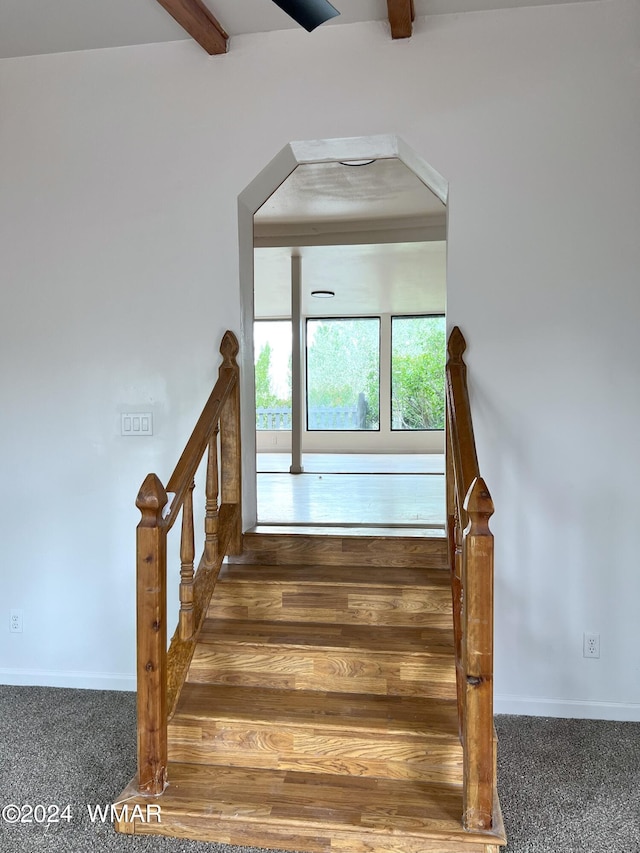 stairs with carpet floors, beam ceiling, and baseboards