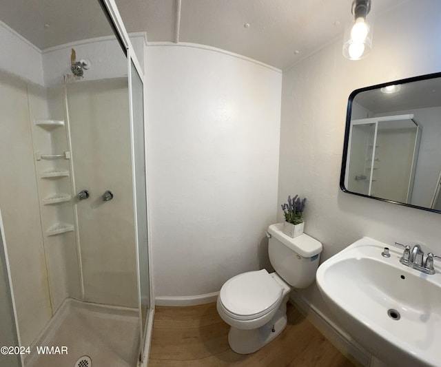 bathroom featuring toilet, a shower stall, a sink, and wood finished floors