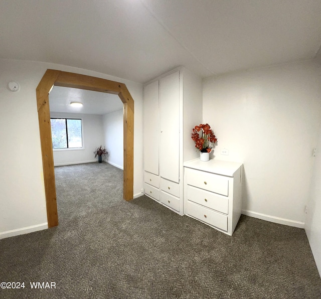 additional living space with baseboards and dark colored carpet