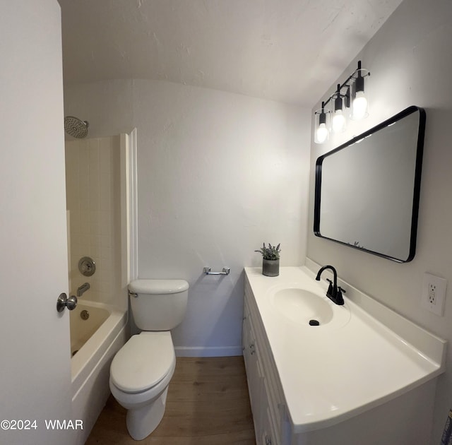 bathroom with toilet, wood finished floors, vanity, baseboards, and washtub / shower combination