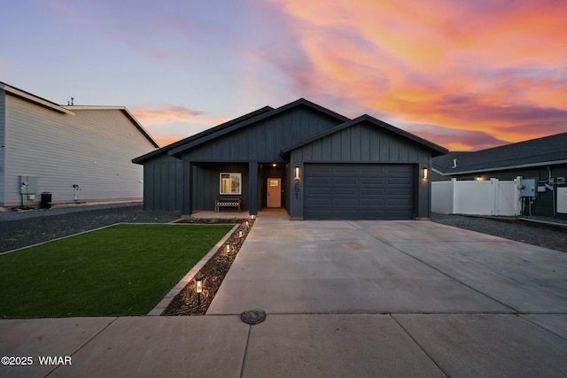 view of front of house featuring an attached garage, fence, driveway, board and batten siding, and a front yard