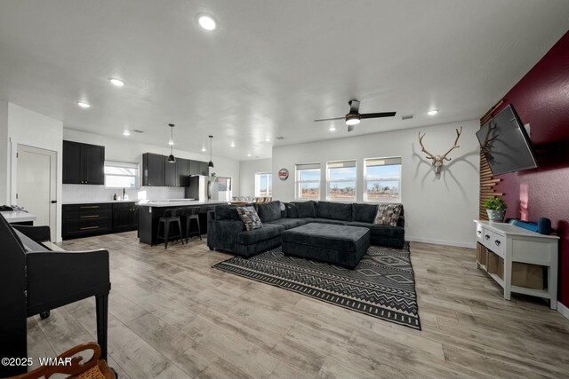 living room with light wood-type flooring, ceiling fan, visible vents, and recessed lighting