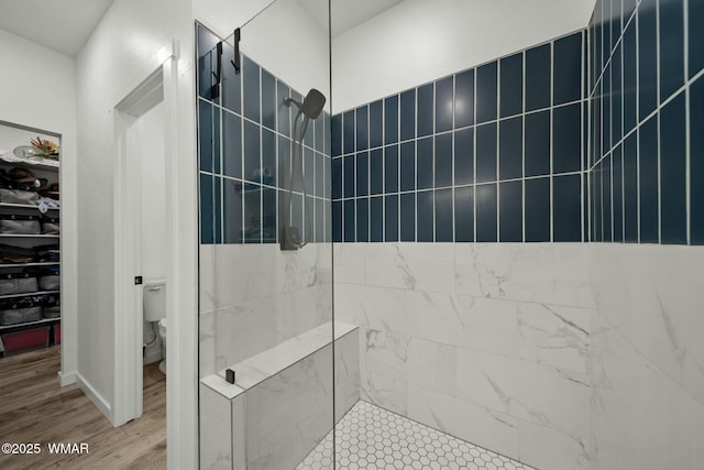 full bath featuring toilet, a walk in shower, and wood finished floors