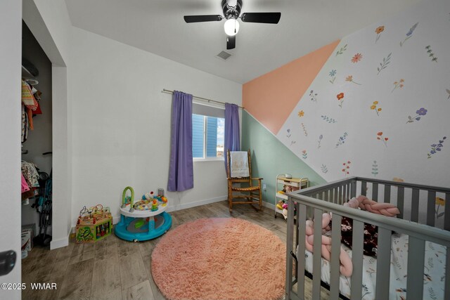 bedroom with a crib, baseboards, and wood finished floors