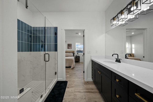 bathroom featuring a marble finish shower, connected bathroom, vanity, wood finished floors, and baseboards