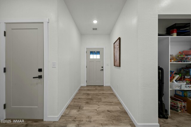 hall with visible vents, light wood-style flooring, and baseboards