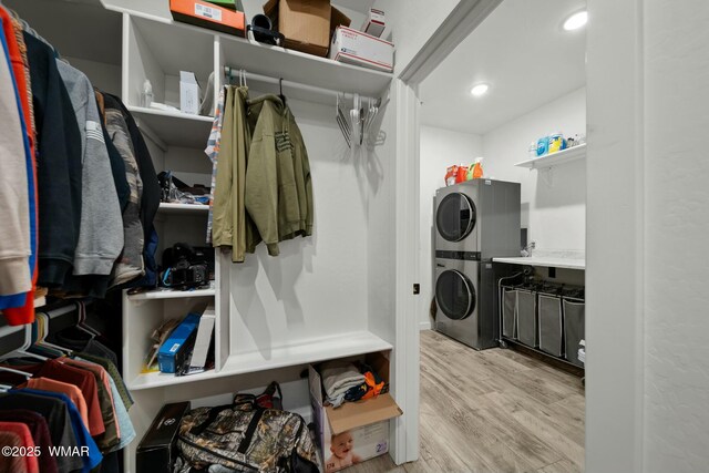 spacious closet with light wood-type flooring and stacked washer and clothes dryer