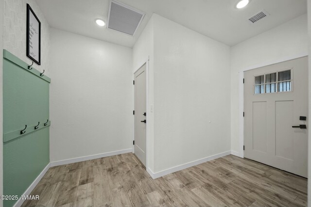 foyer featuring light wood finished floors, baseboards, and visible vents