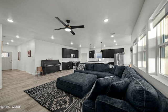 living room featuring visible vents, baseboards, a ceiling fan, light wood-style flooring, and recessed lighting