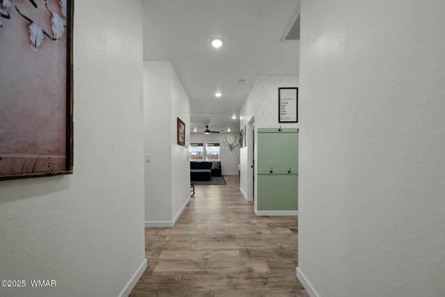 hallway with light wood-style flooring, recessed lighting, visible vents, and baseboards