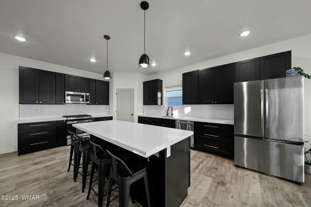 kitchen featuring a breakfast bar area, stainless steel appliances, light countertops, a center island, and pendant lighting