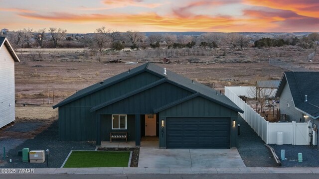 view of front of house featuring a garage, concrete driveway, board and batten siding, and fence