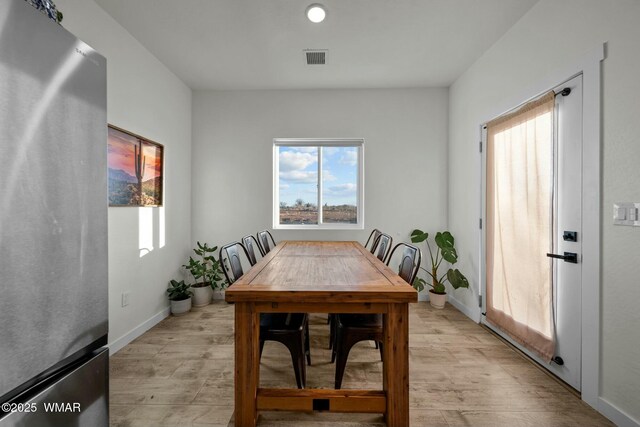 dining space with baseboards, visible vents, and light wood-style floors