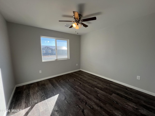 unfurnished room featuring visible vents, dark wood finished floors, and baseboards