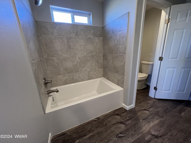 bathroom with toilet, washtub / shower combination, and wood finished floors