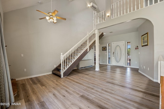 6853 Rim Rock Rd, Show Low, AZ 85901 - entrance foyer with arched walkways, a ceiling fan, stairway, wood finished floors, and a high ceiling