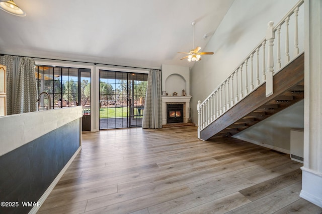 6853 Rim Rock Rd, Show Low, AZ 85901 - unfurnished living room with a ceiling fan, a glass covered fireplace, wood finished floors, stairway, and lofted ceiling