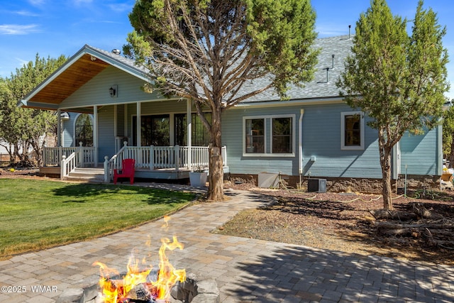 6853 Rim Rock Rd, Show Low, AZ 85901 - view of front of property featuring a fire pit, a front yard, a porch, and a shingled roof